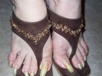 Long yellow toenails in beaded sandals